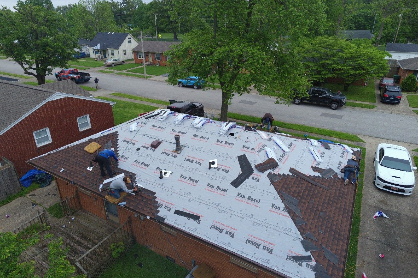 An aerial view of a roof being repaired in a residential area.