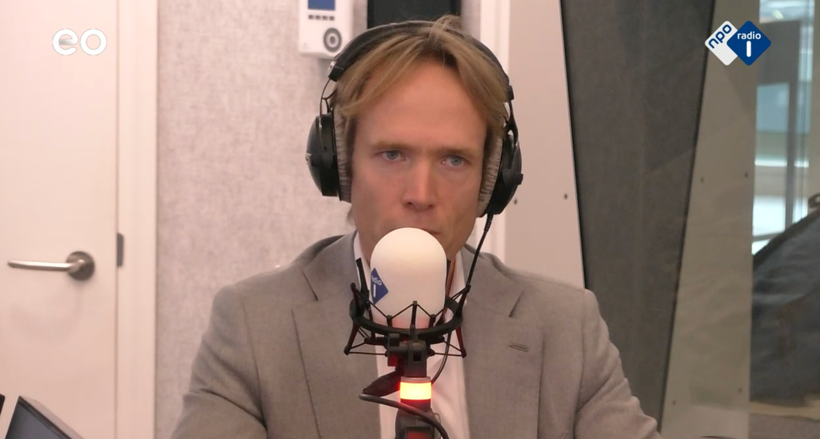 Een man met een koptelefoon praat in een microfoon