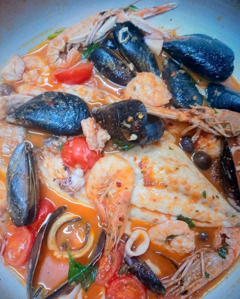 Un primo piano di un piatto di cibo con frutti di mare e pomodori