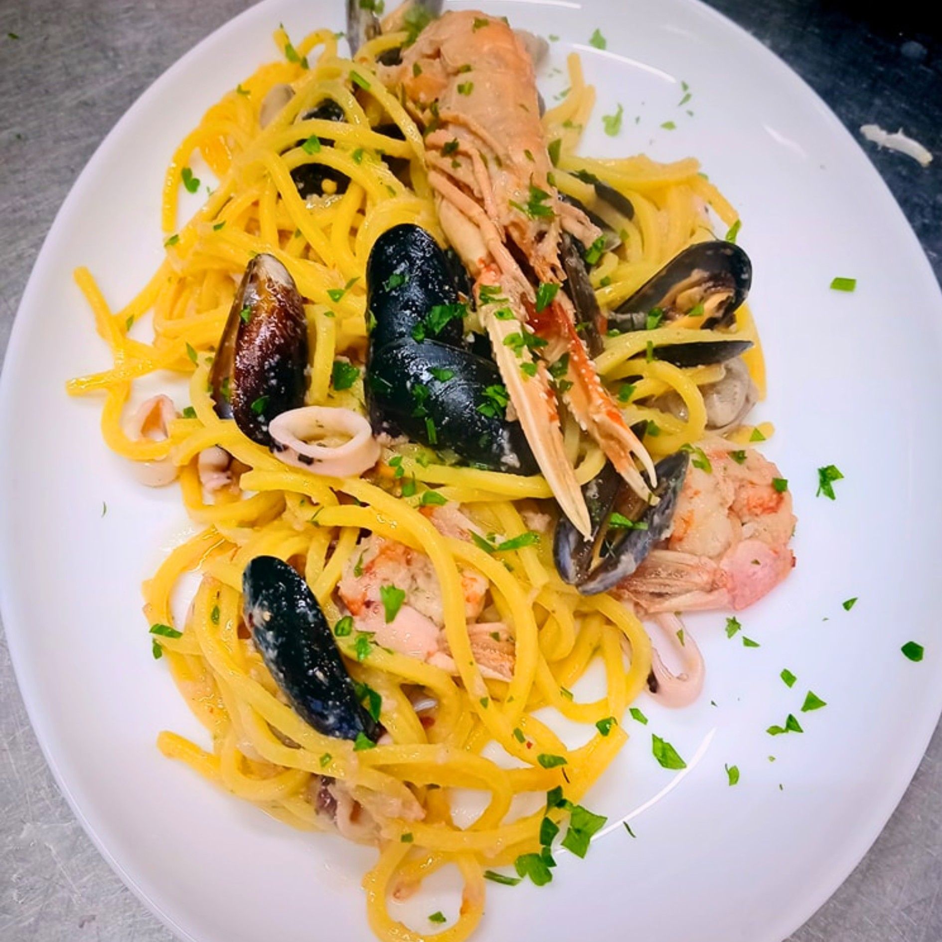 Un piatto bianco condito con spaghetti e frutti di mare