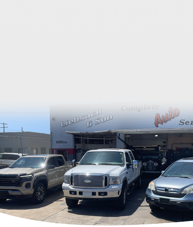 A red truck is parked in a parking lot next to a white truck. | Liebsack Auto Services