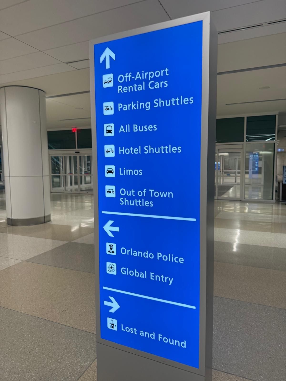A blue sign shows directions to off airport rental cars parking shuttles all buses hotel shuttles and more