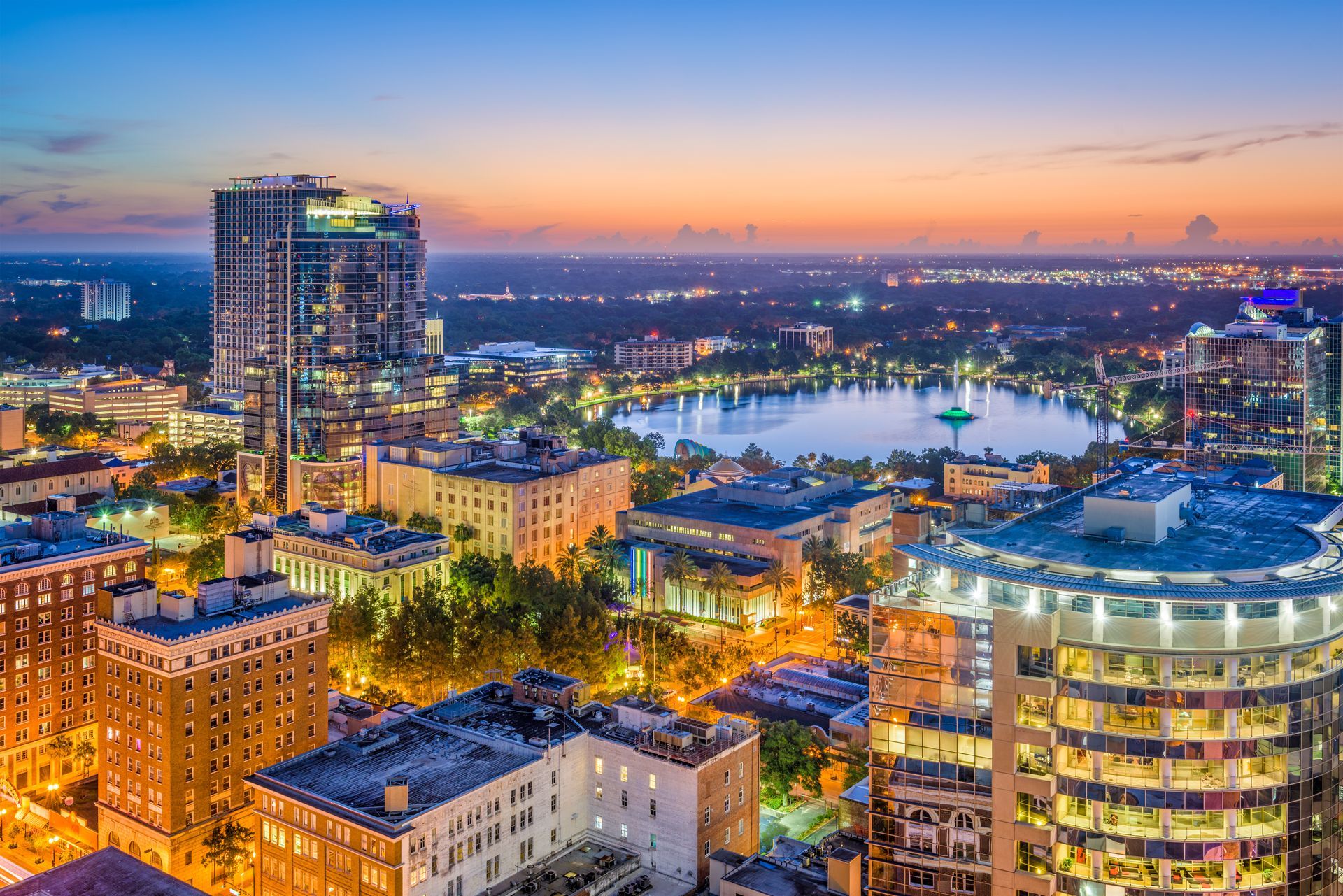 An aerial view of a city at night with a lake in the background.