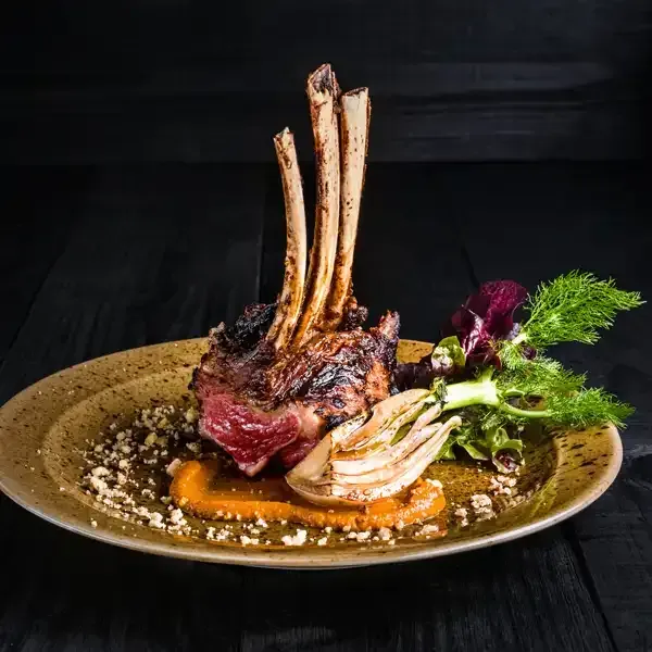 A plate of food with meat and vegetables on a wooden table.