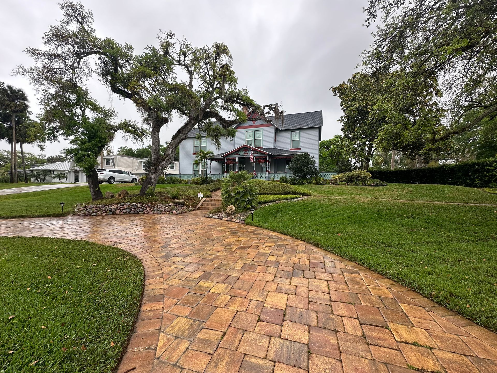 There is a brick walkway leading to a large house.