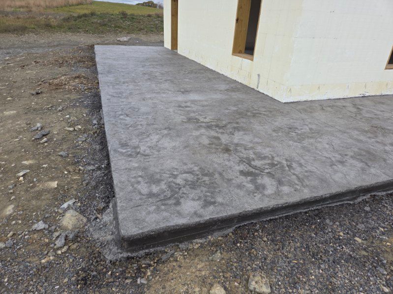 Concrete slab next to a building under construction, on a gravel surface.