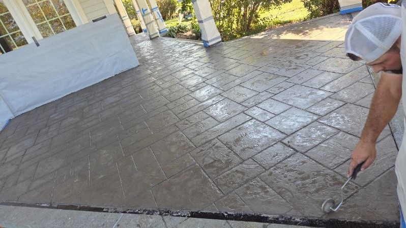 Man applying a sealant to stamped concrete patio.
