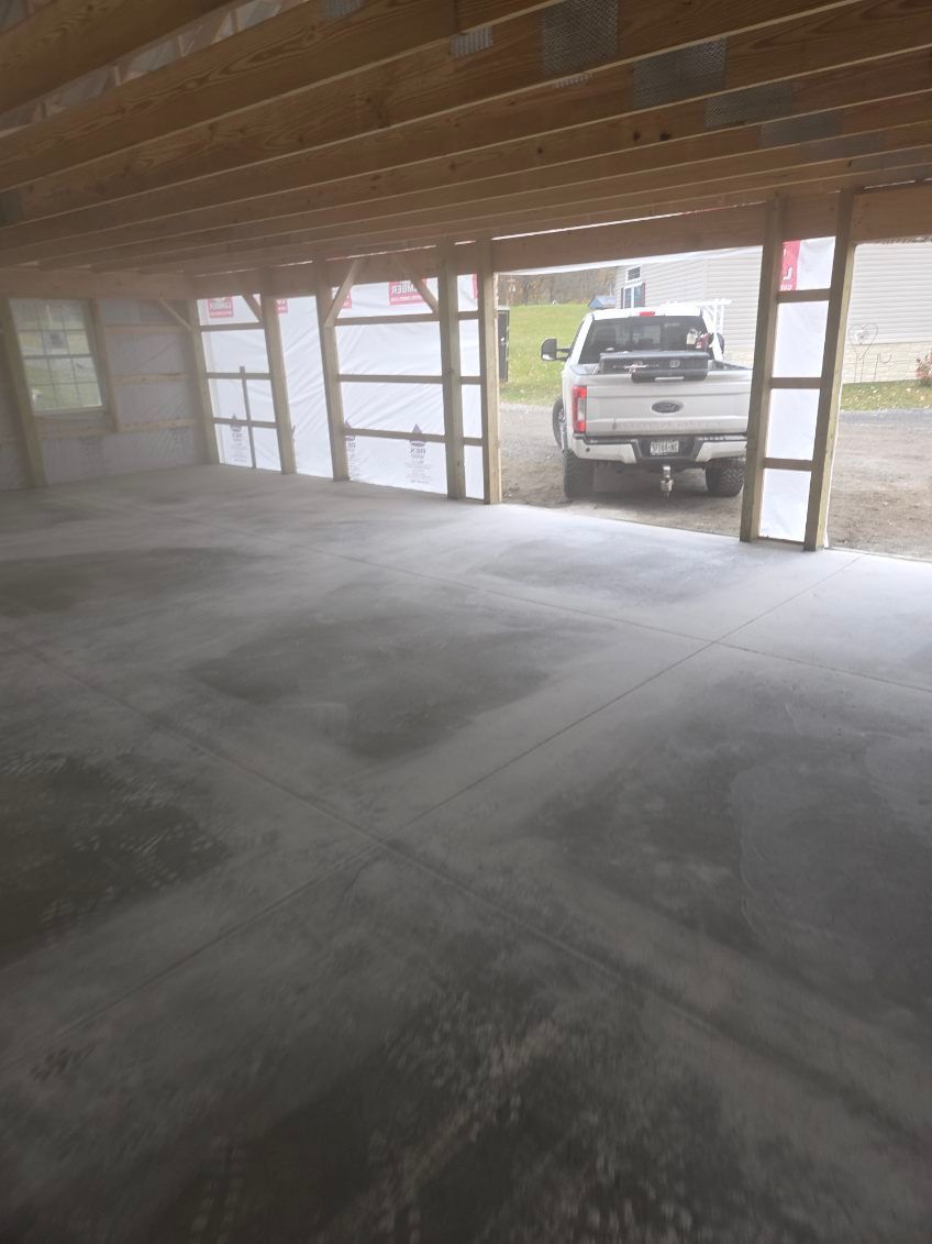 White truck parked in an open garage with exposed wooden beams, concrete floor, and plastic sheeting.