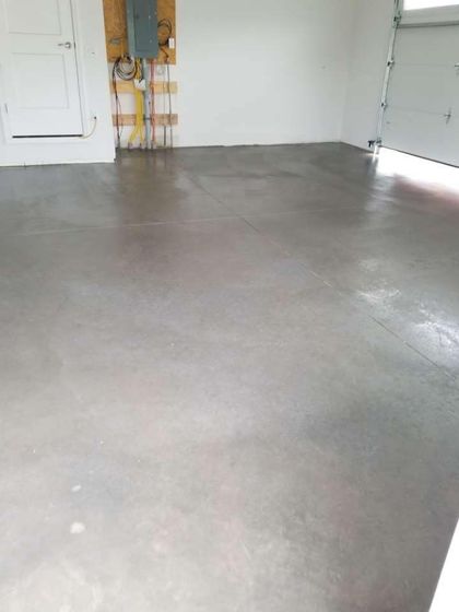 Empty garage with a polished concrete floor, white walls, and a partially open garage door.