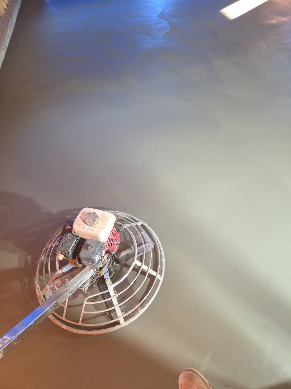 A concrete floor being smoothed with a power trowel.