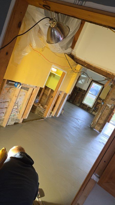 Interior renovation: Concrete floor, exposed wall studs, and overhead work light.