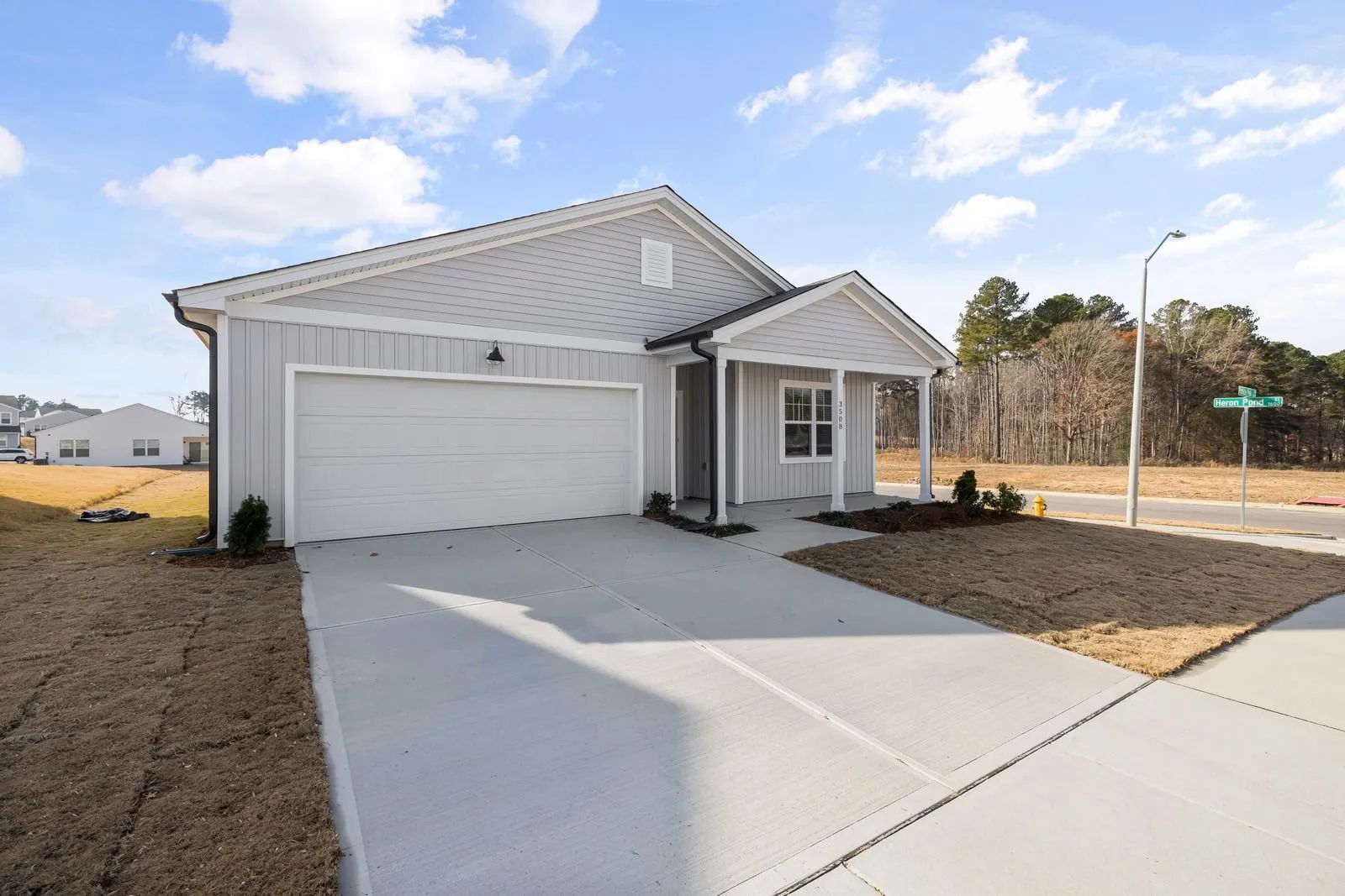 Suburban single-story house with a two-car garage, white exterior, and concrete driveway