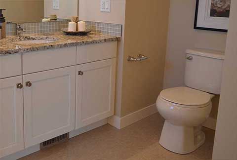 A bathroom with a toilet , sink and mirror.