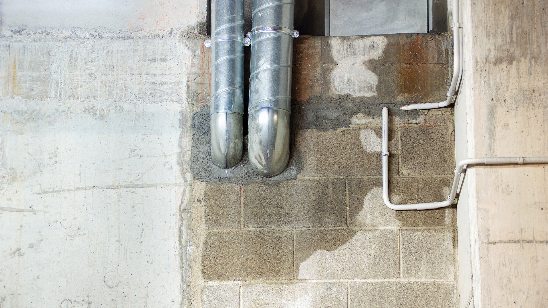 A close up of a brick wall with pipes coming out of it.