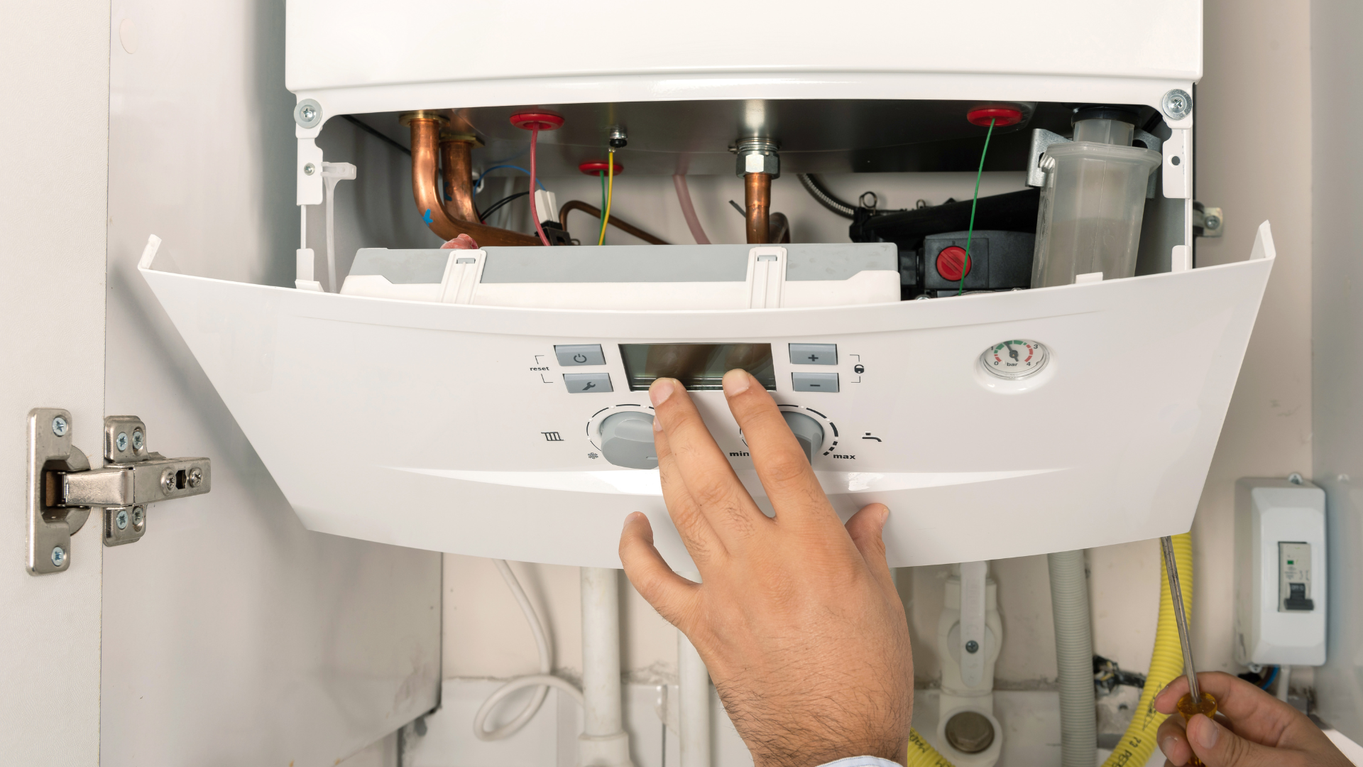 A person is working on a boiler in a cabinet.