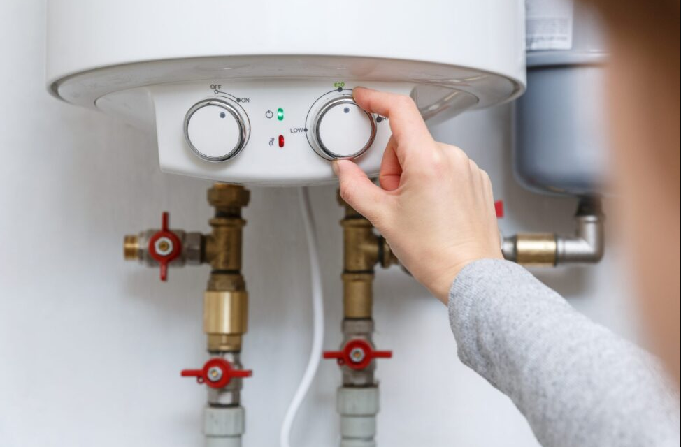 A person is adjusting the temperature of a water heater.