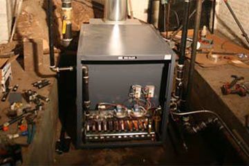 A boiler is being repaired in a basement.