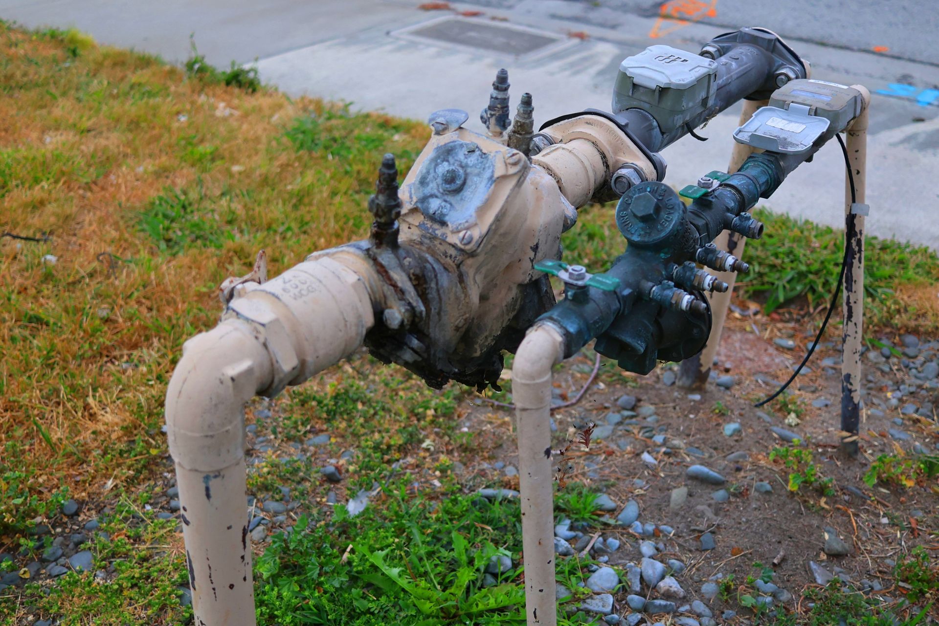 A water meter is attached to a pipe in the grass.