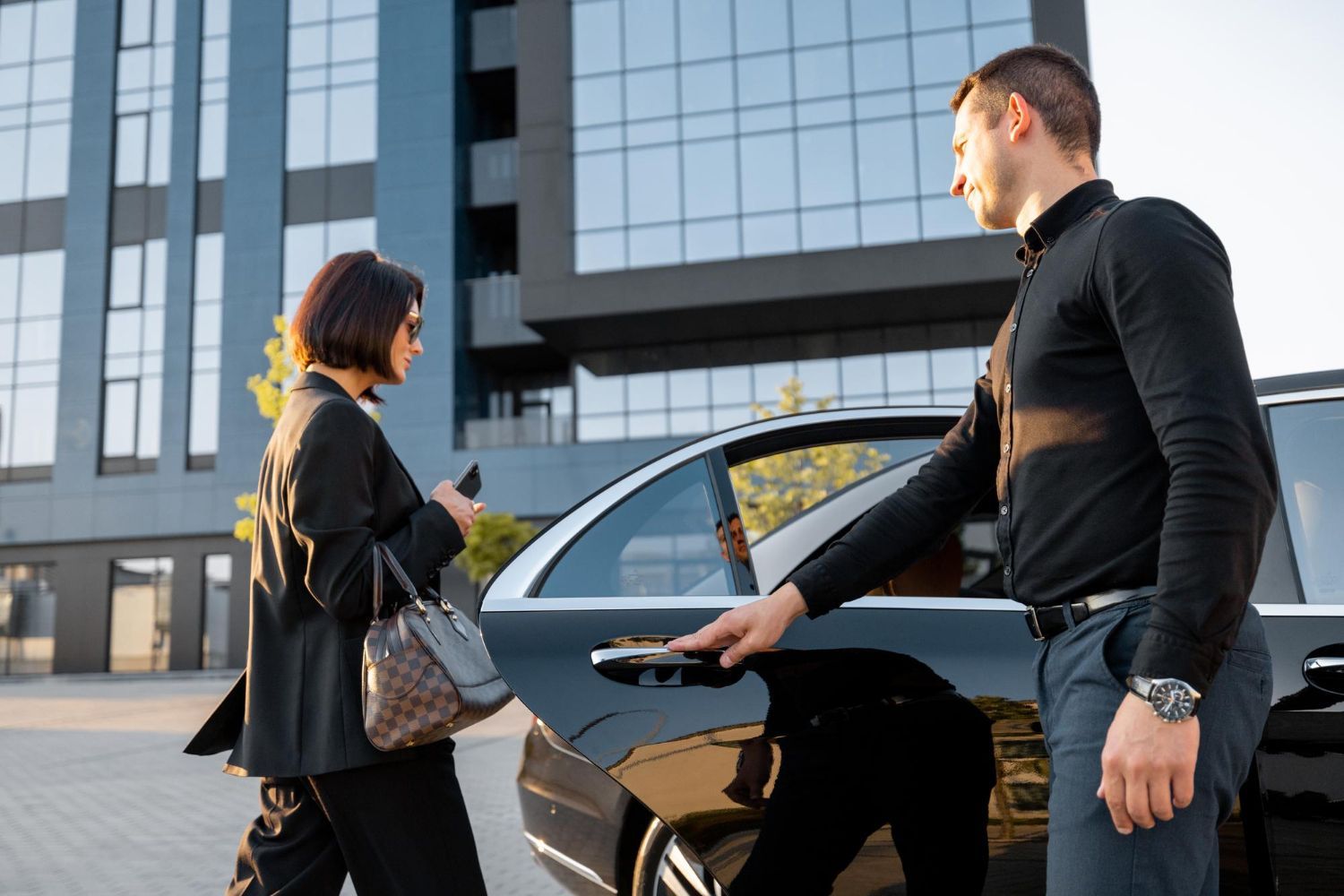 Man opening car door for a woman in front of a modern building.