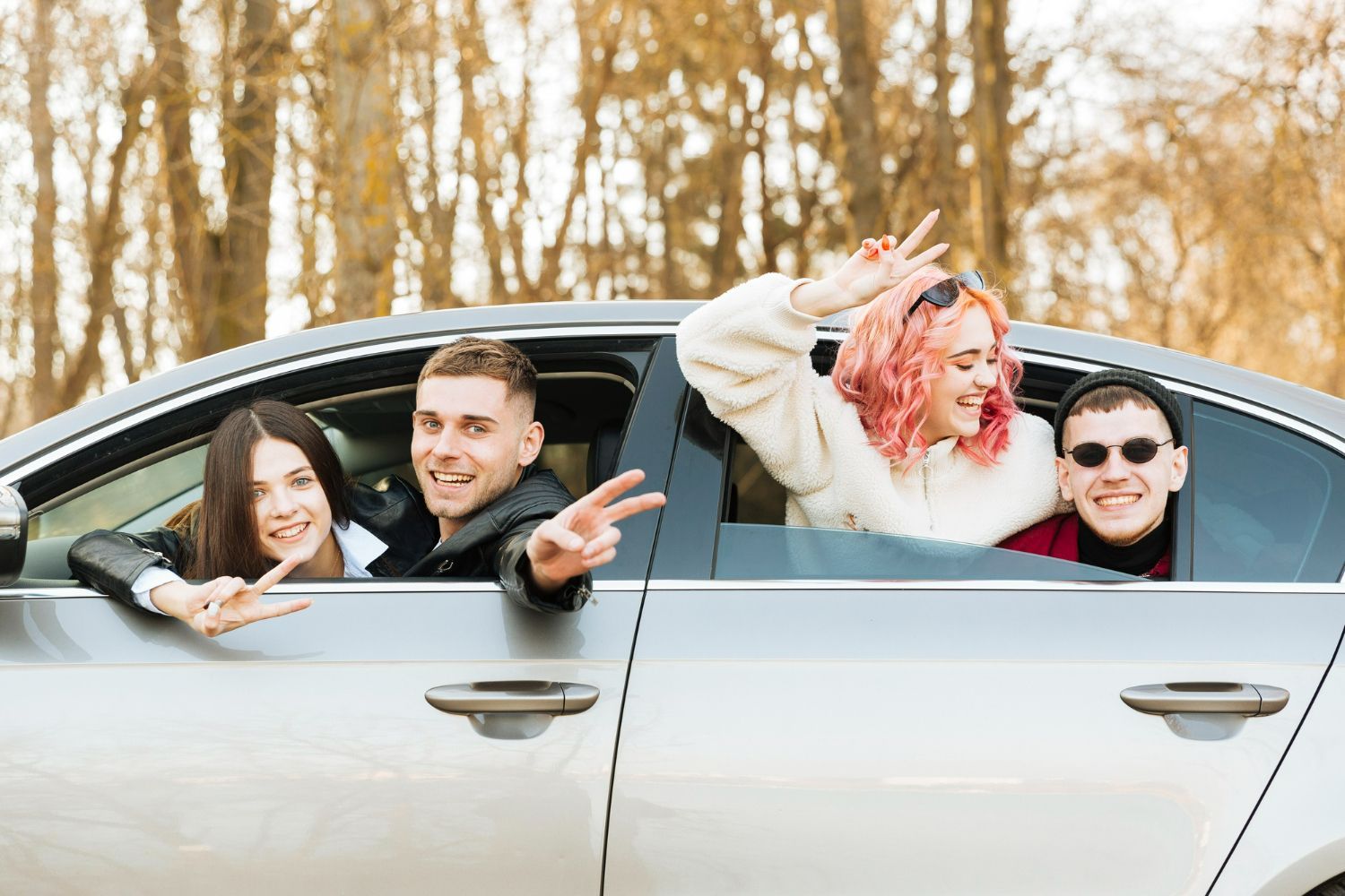 A group of young people are sitting in a car with their heads out the window.