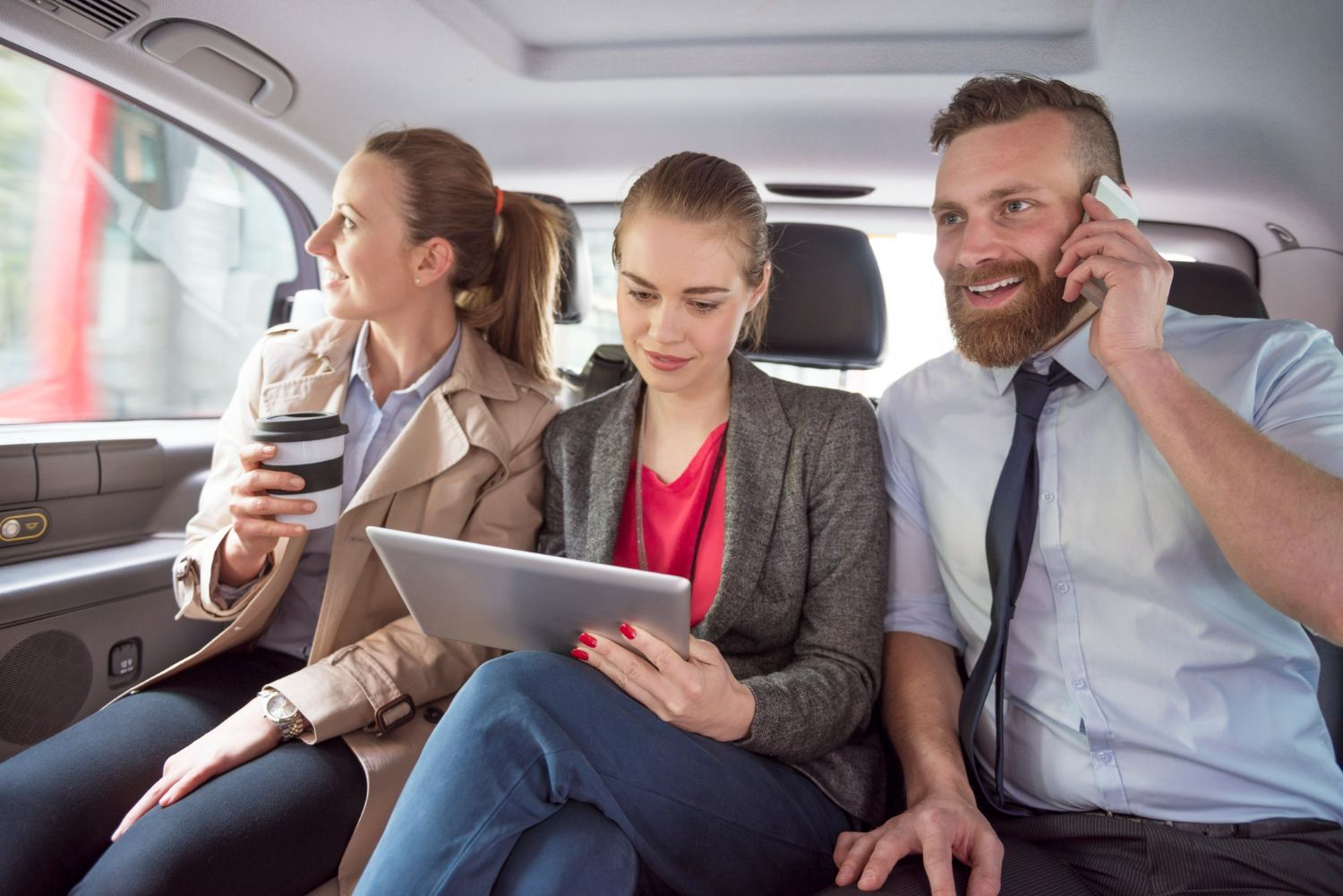 A man is talking on a cell phone while a woman looks at a tablet.