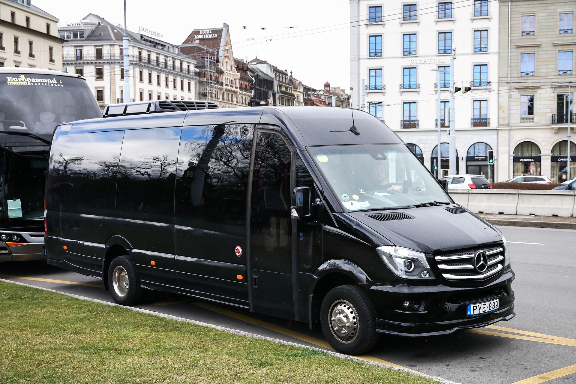 A black van is parked in a parking lot in front of a building.