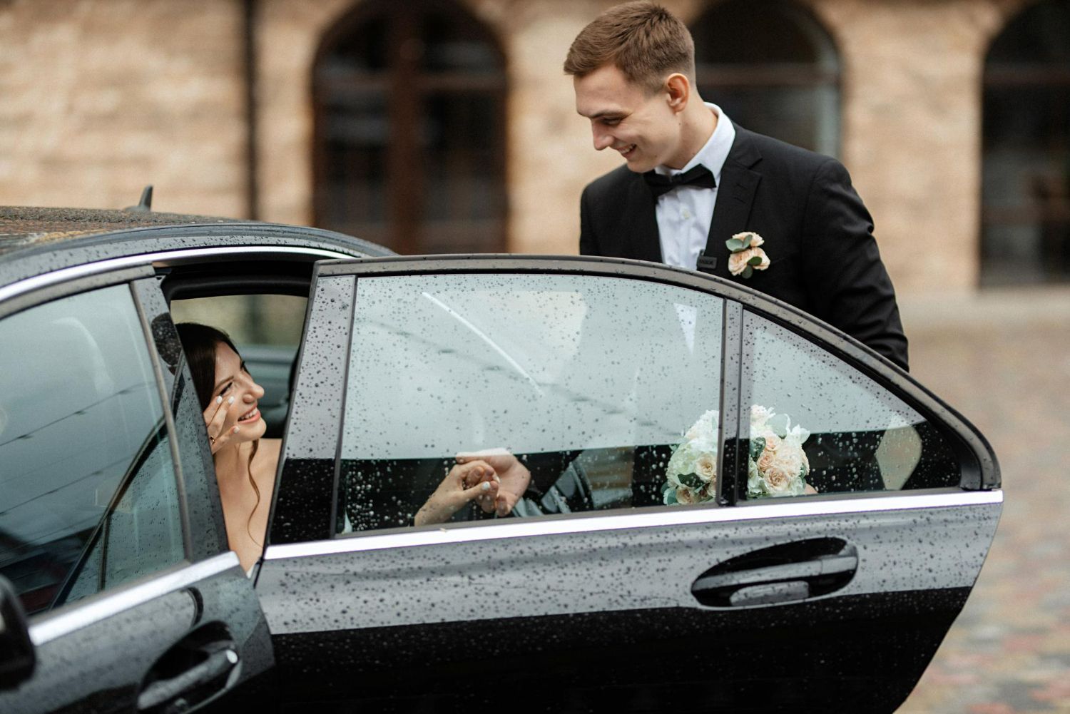 A bride and groom are getting out of a car.