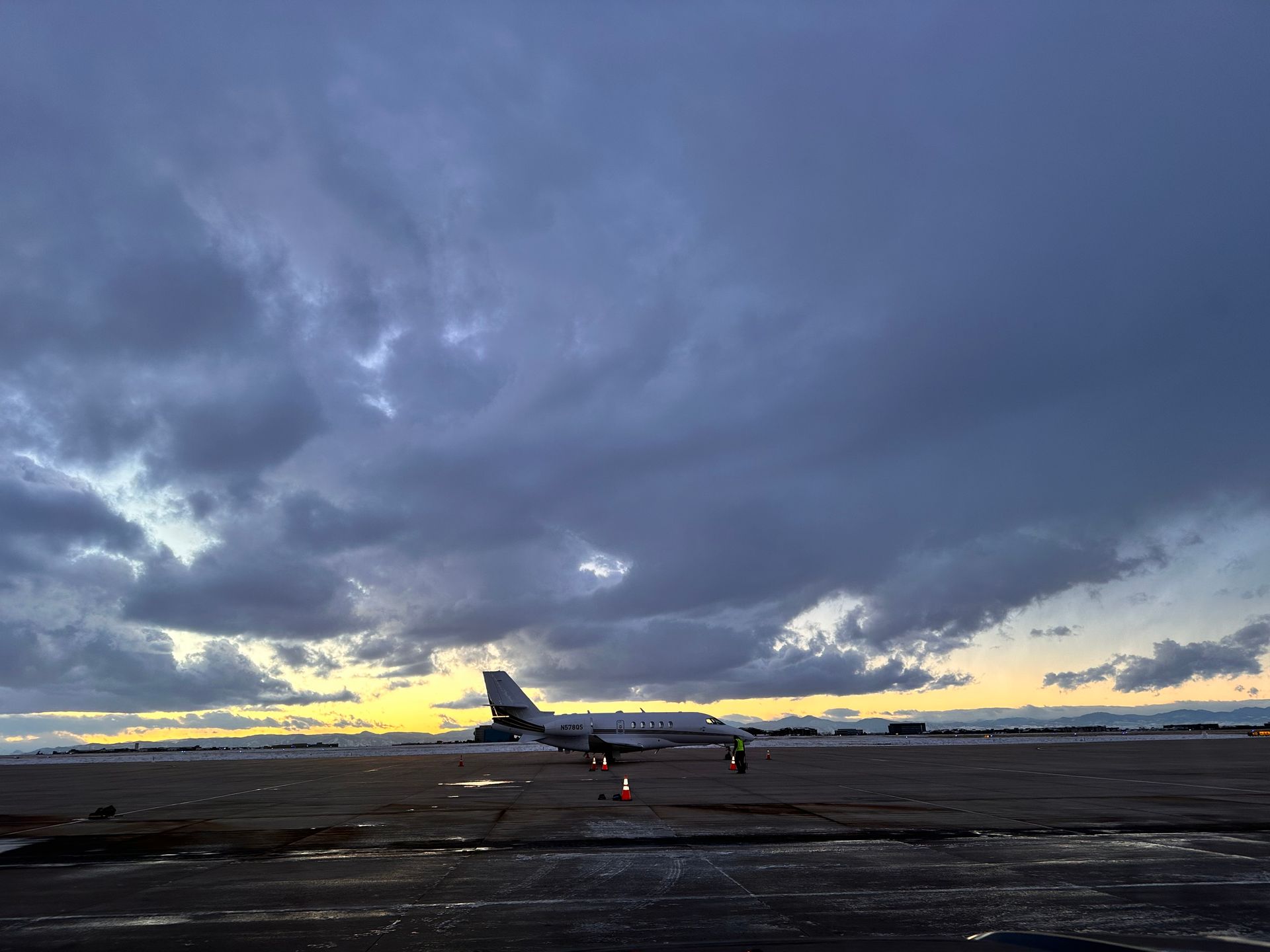 Airplane on a wet tarmac under a cloudy sky at dusk.