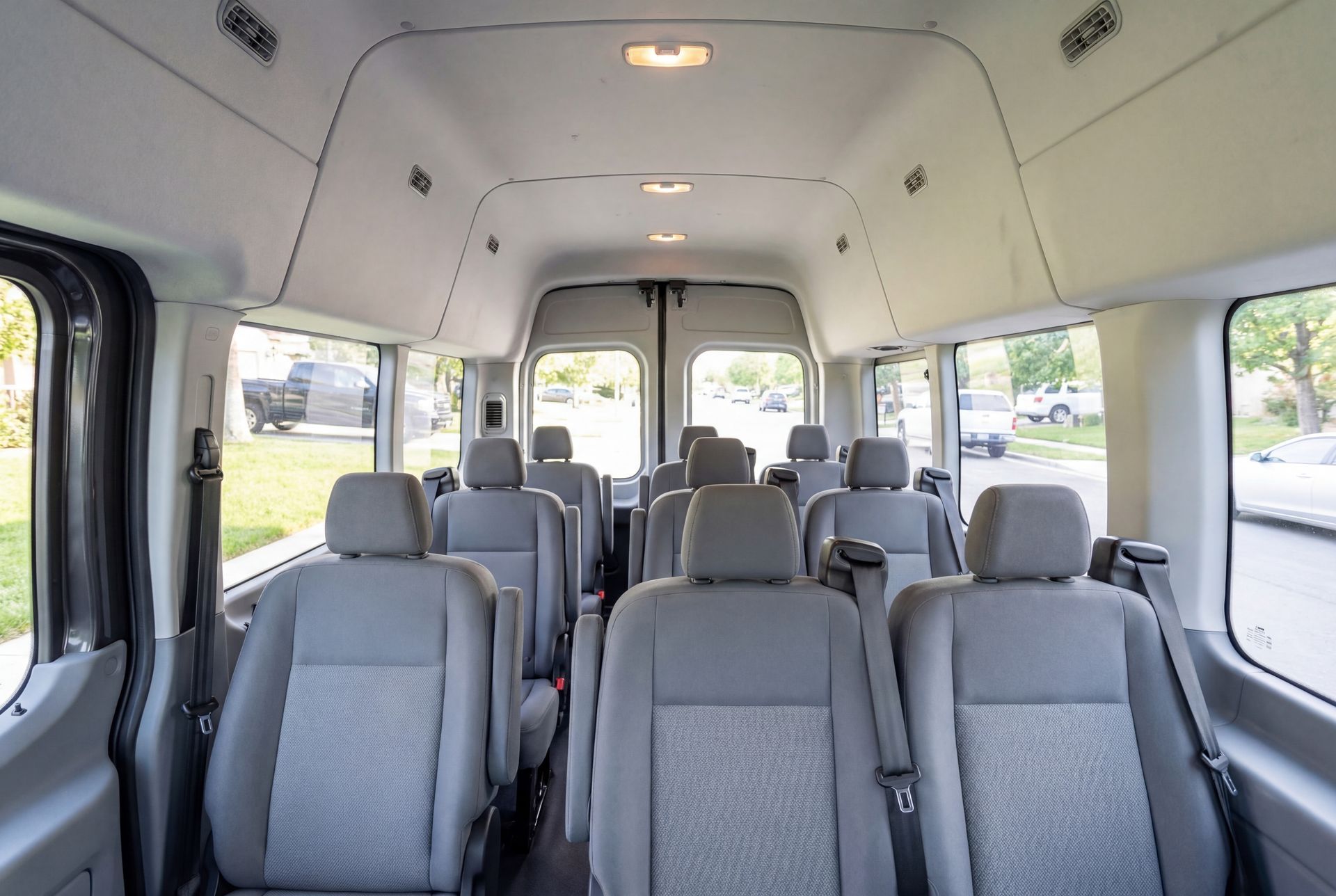 Interior of a passenger van with rows of gray seats and windows.