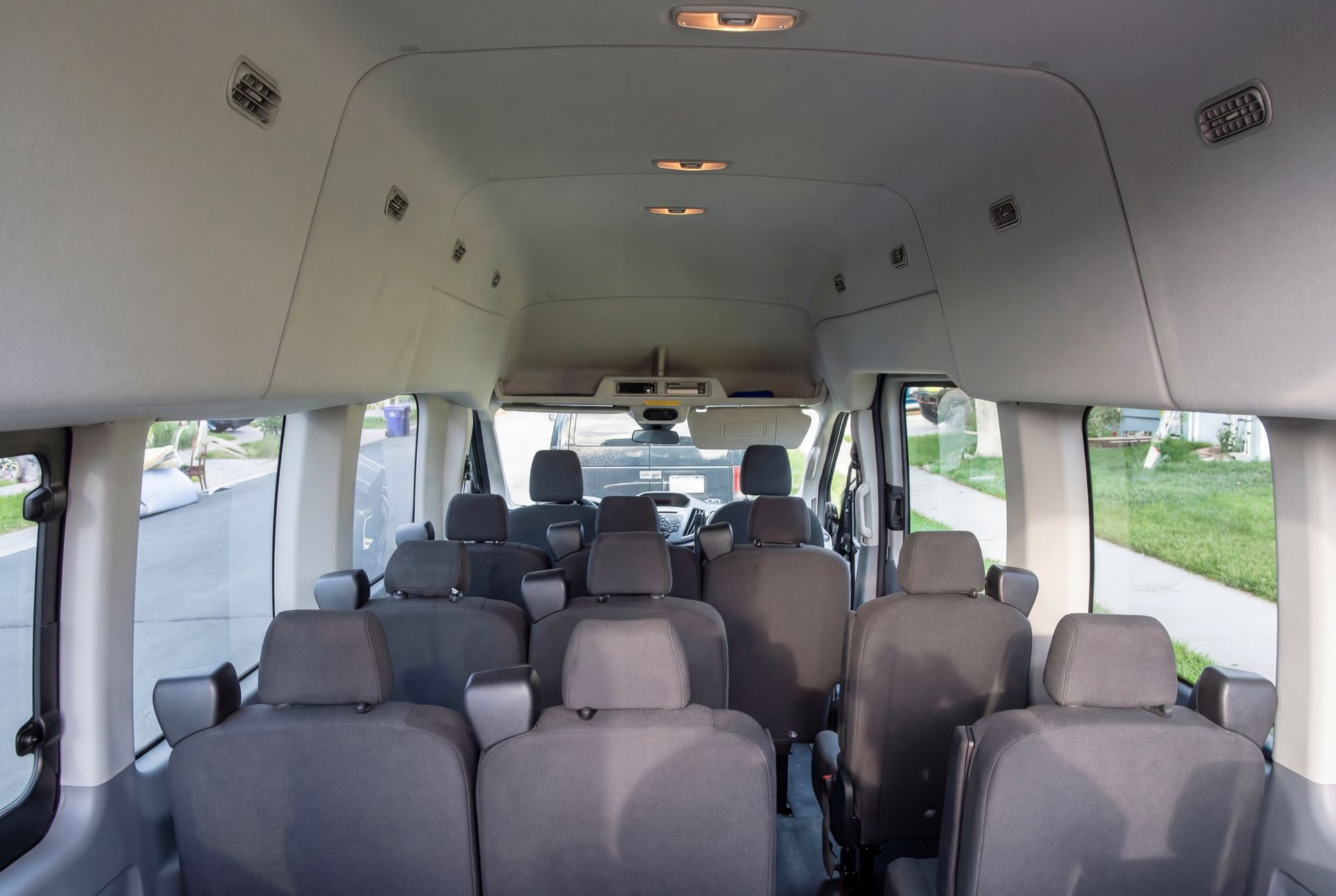 Interior of a passenger van with multiple gray seats. The vehicle is empty.