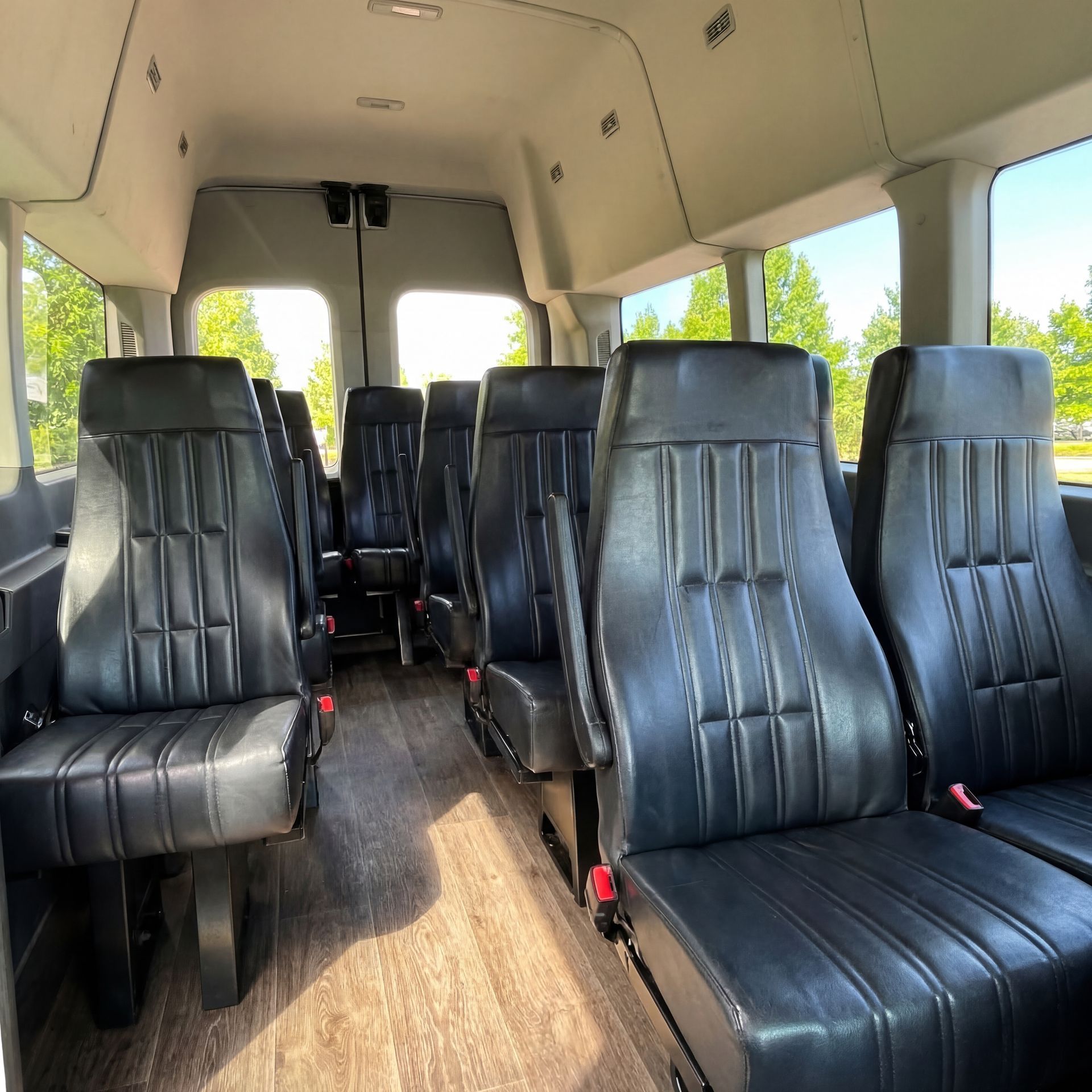 Interior of a passenger van with rows of black leather seats.
