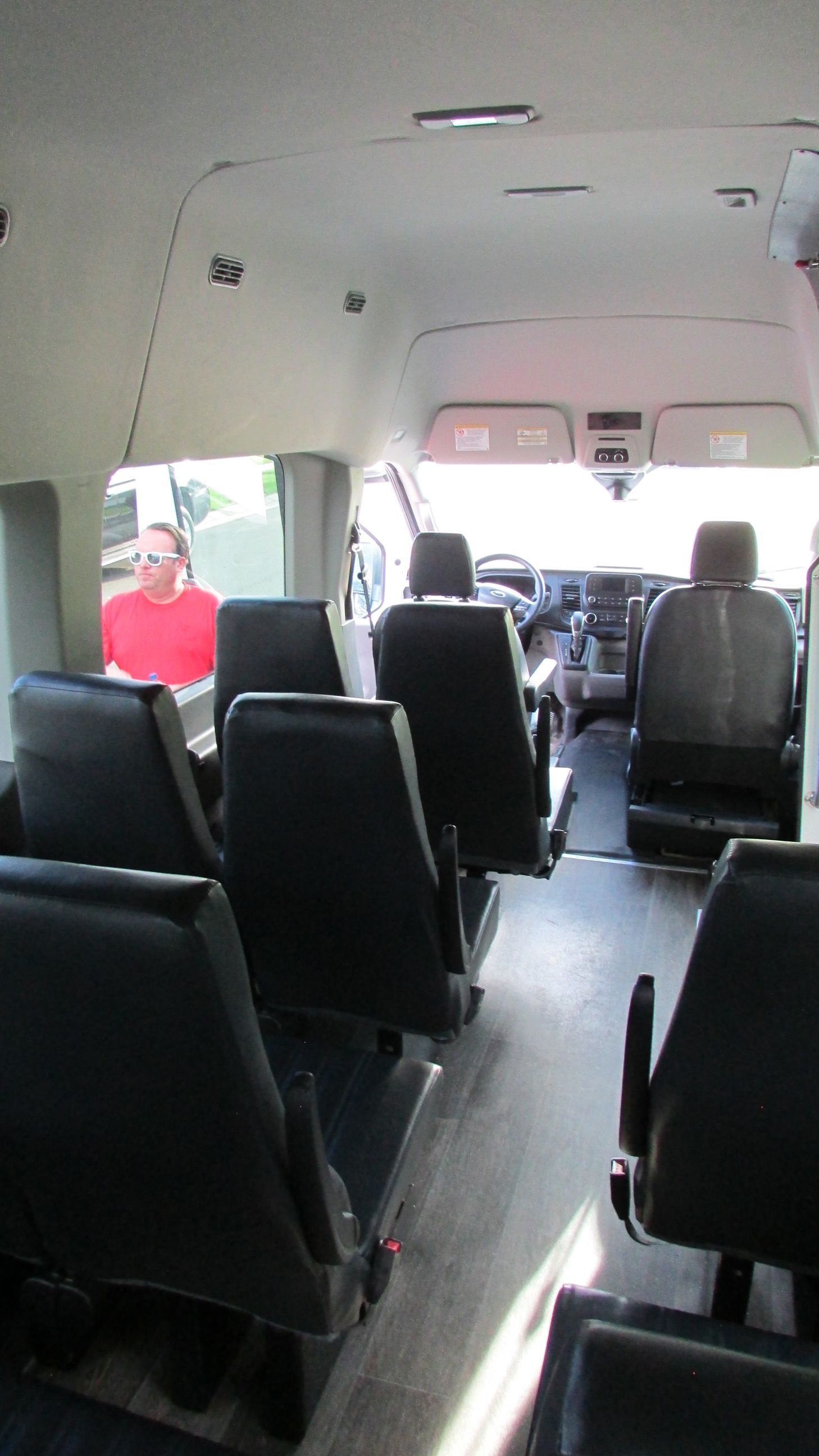 The inside of a bus with a lot of seats and a man in a red shirt.