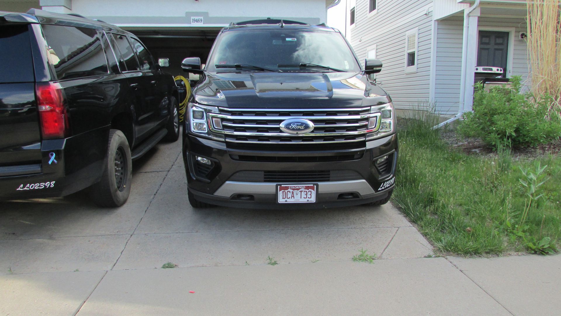 A black ford expedition is parked in a driveway next to a suburban suv.