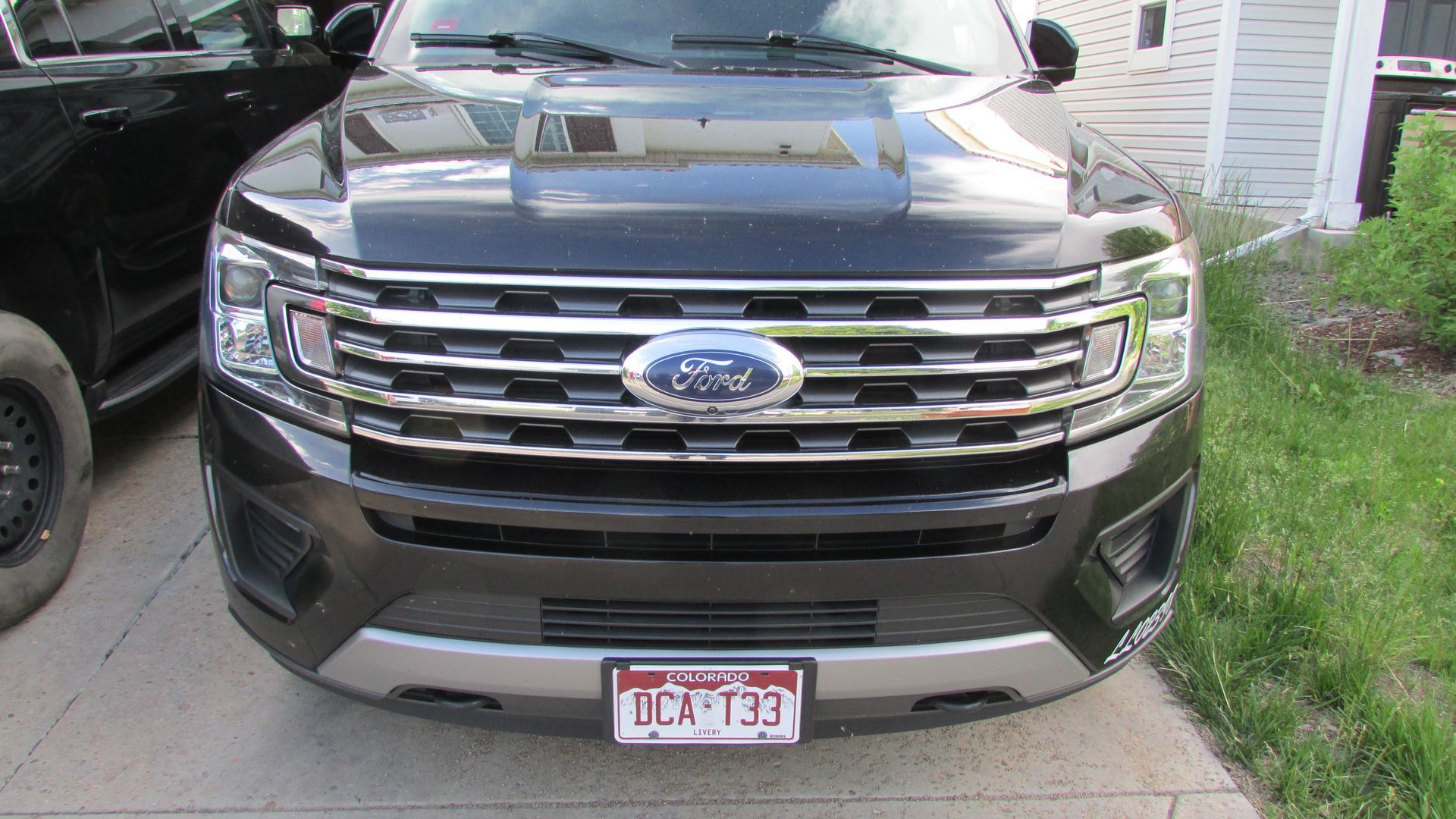 A black ford expedition is parked on the sidewalk in front of a house.