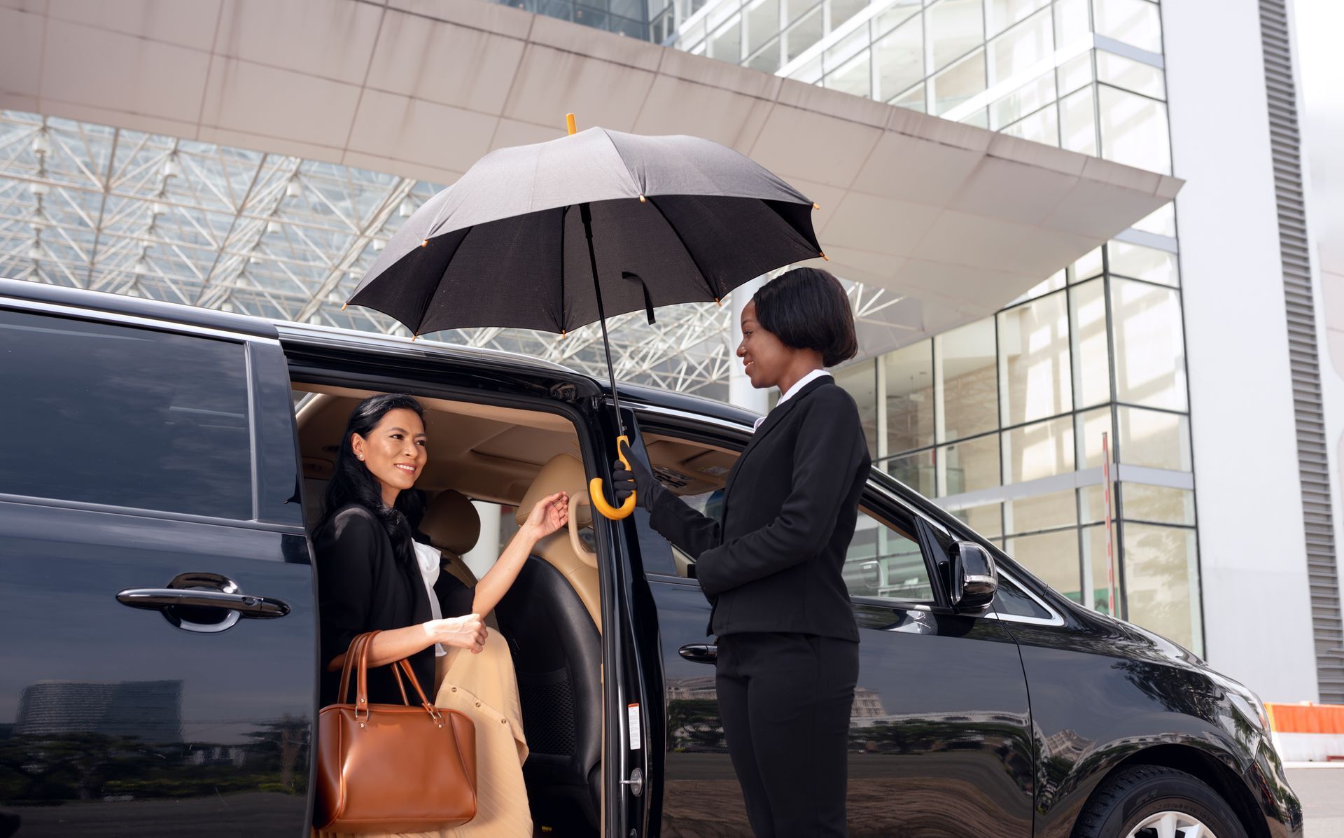A woman is getting out of a car with an umbrella.