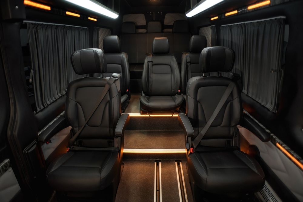 The interior of a van with a lot of black leather seats.
