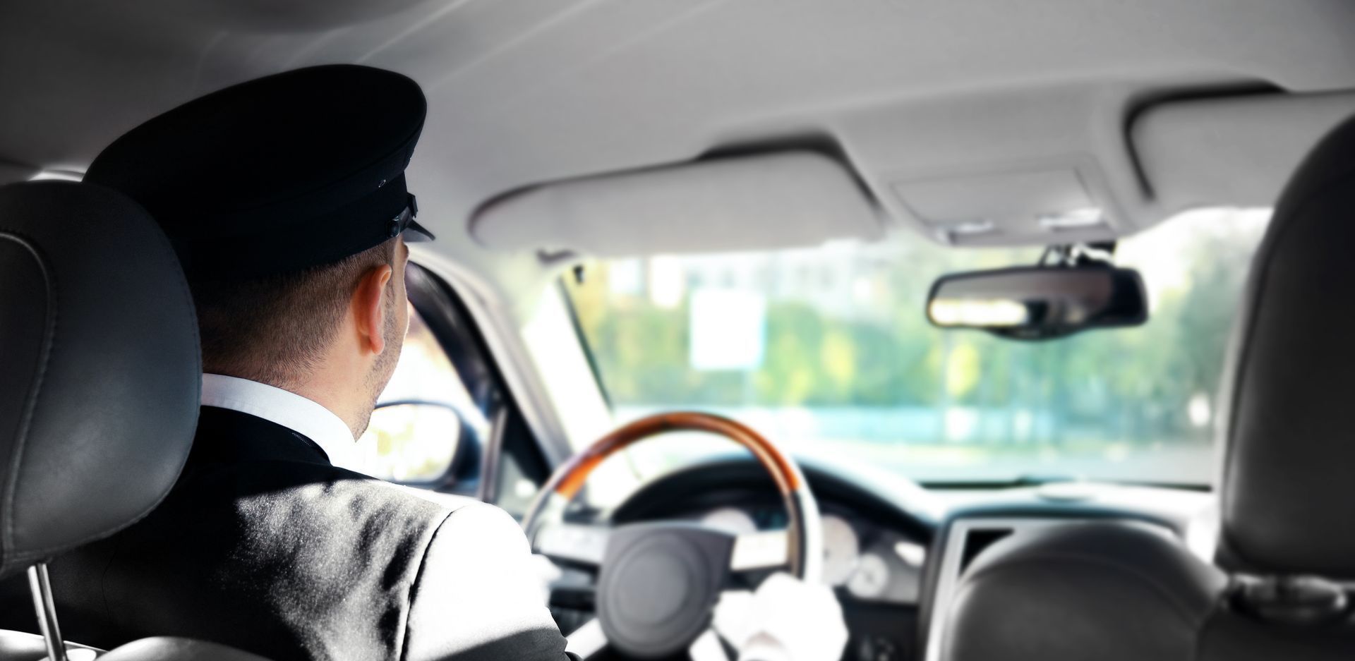 A man in a black hat is driving a car