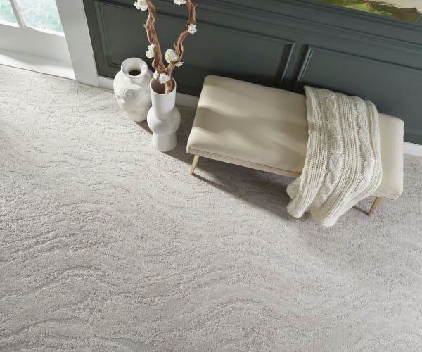 There is a bench with a blanket on it and vases on the floor.