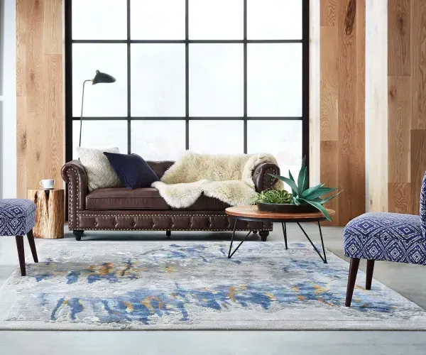 A living room with a couch , chairs , and a rug.