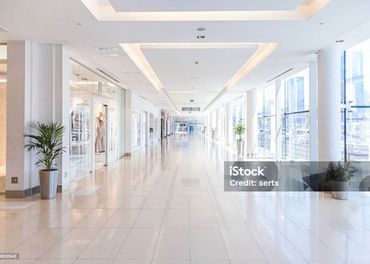 A long empty hallway in a shopping mall with lots of windows.