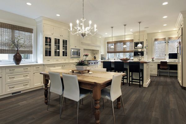 A kitchen with a wooden table and chairs and a chandelier.