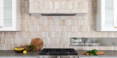 A kitchen with a stove top oven and a hood above it.