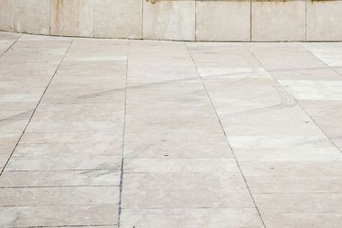 A close up of a tiled floor with a wall in the background.