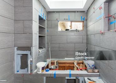 A bathroom is being remodeled with tiles and a window.