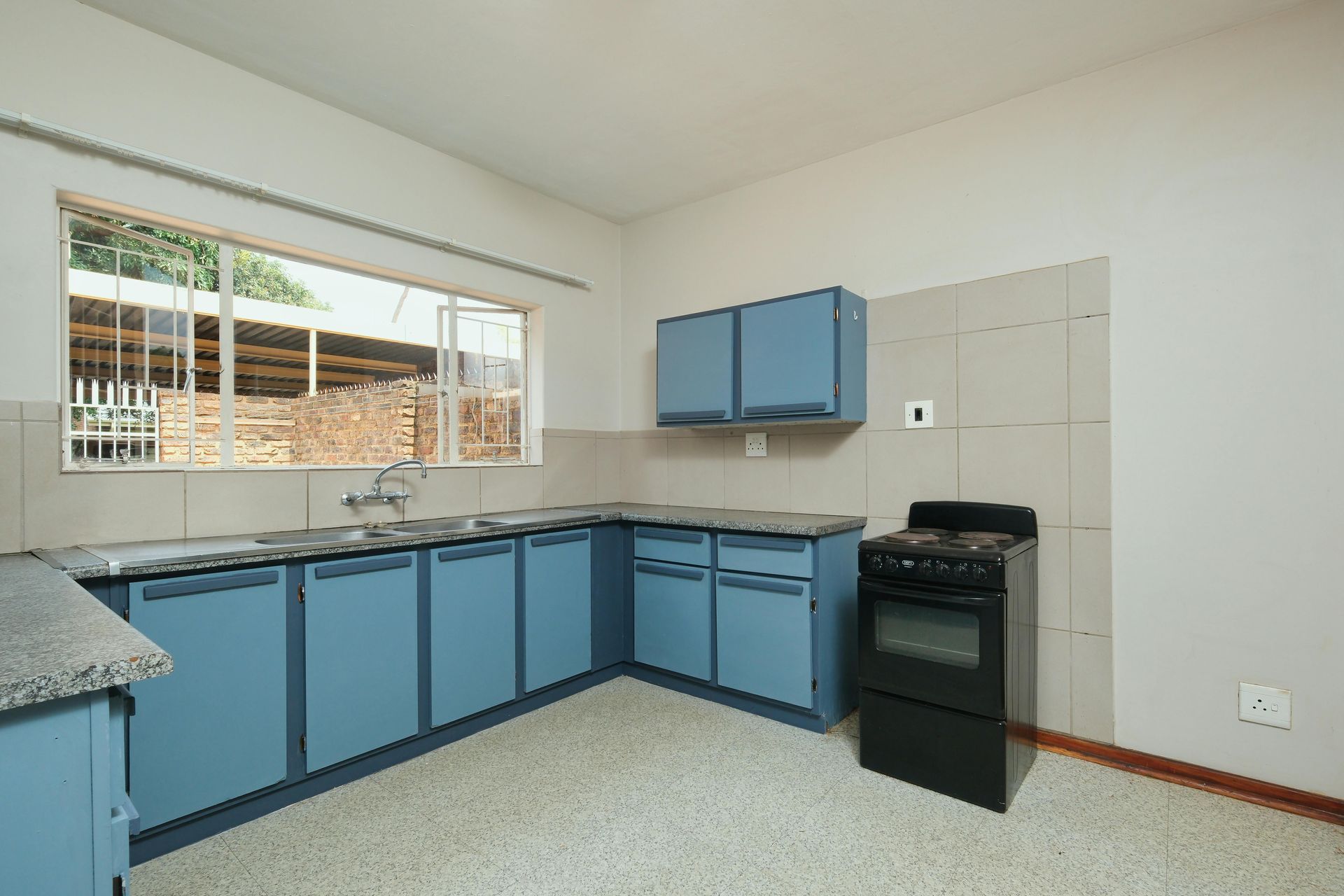 An empty kitchen with blue cabinets and a black stove