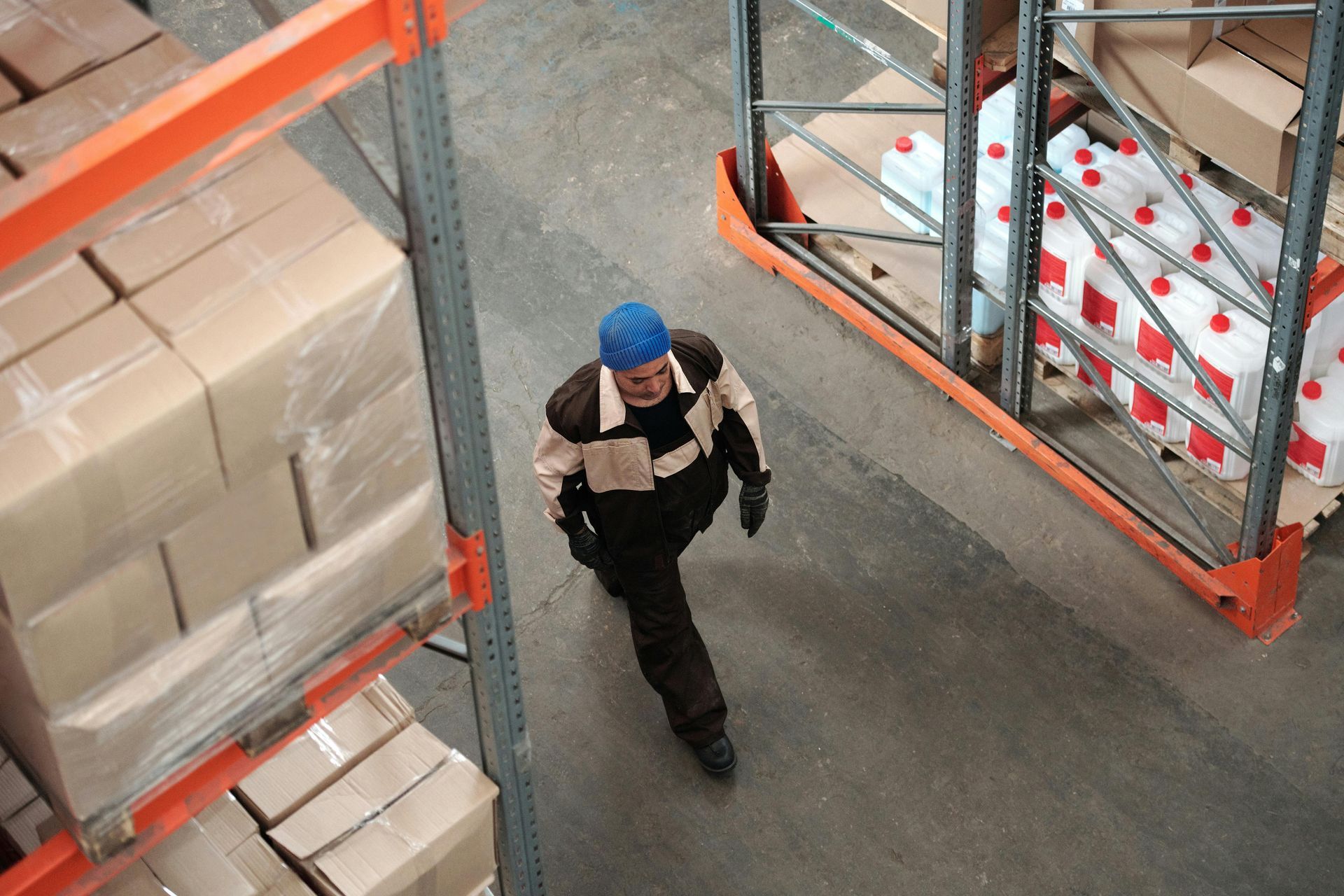 A man is walking through a warehouse filled with lots of boxes.