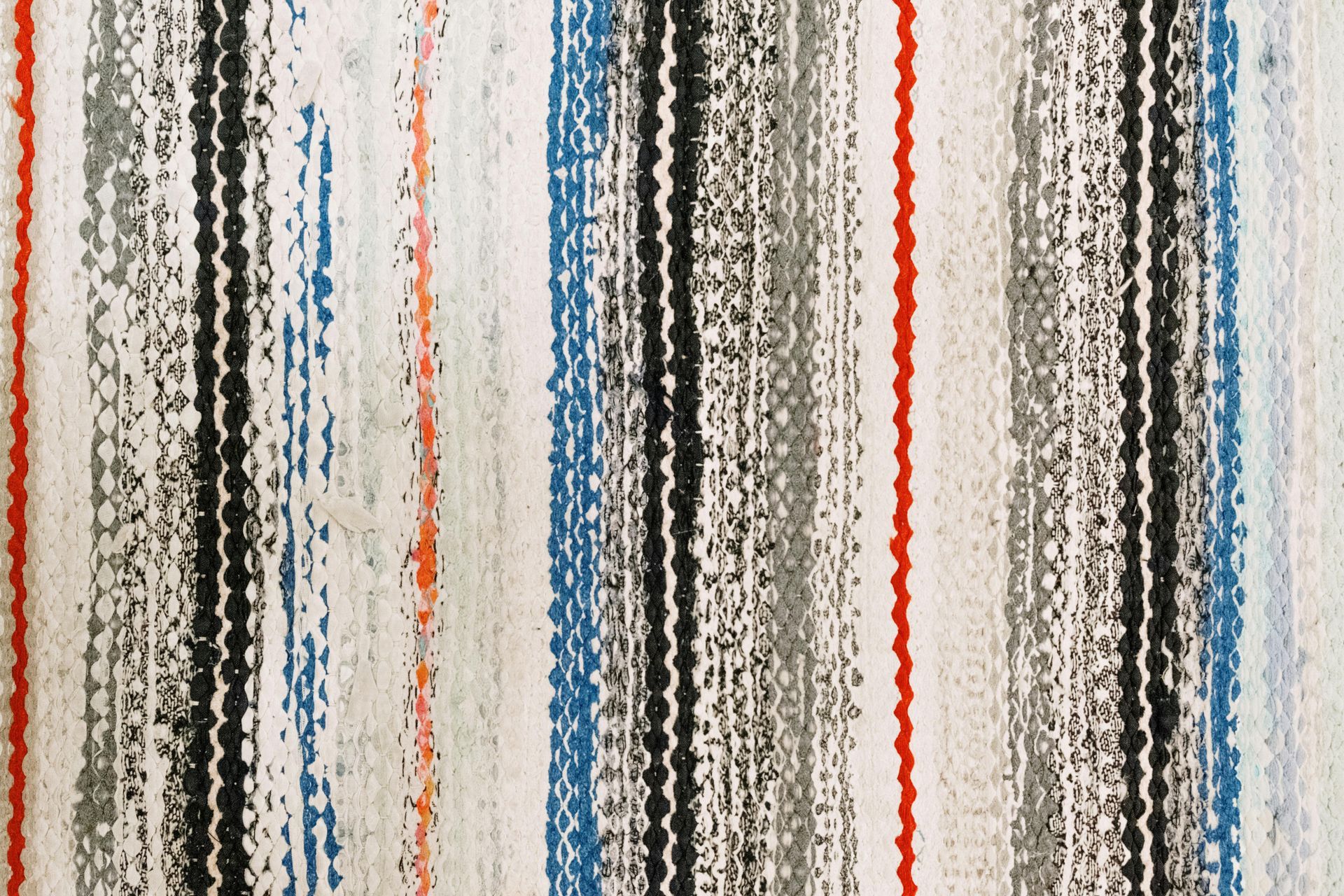 A close up of a striped rug with red , black and blue stripes