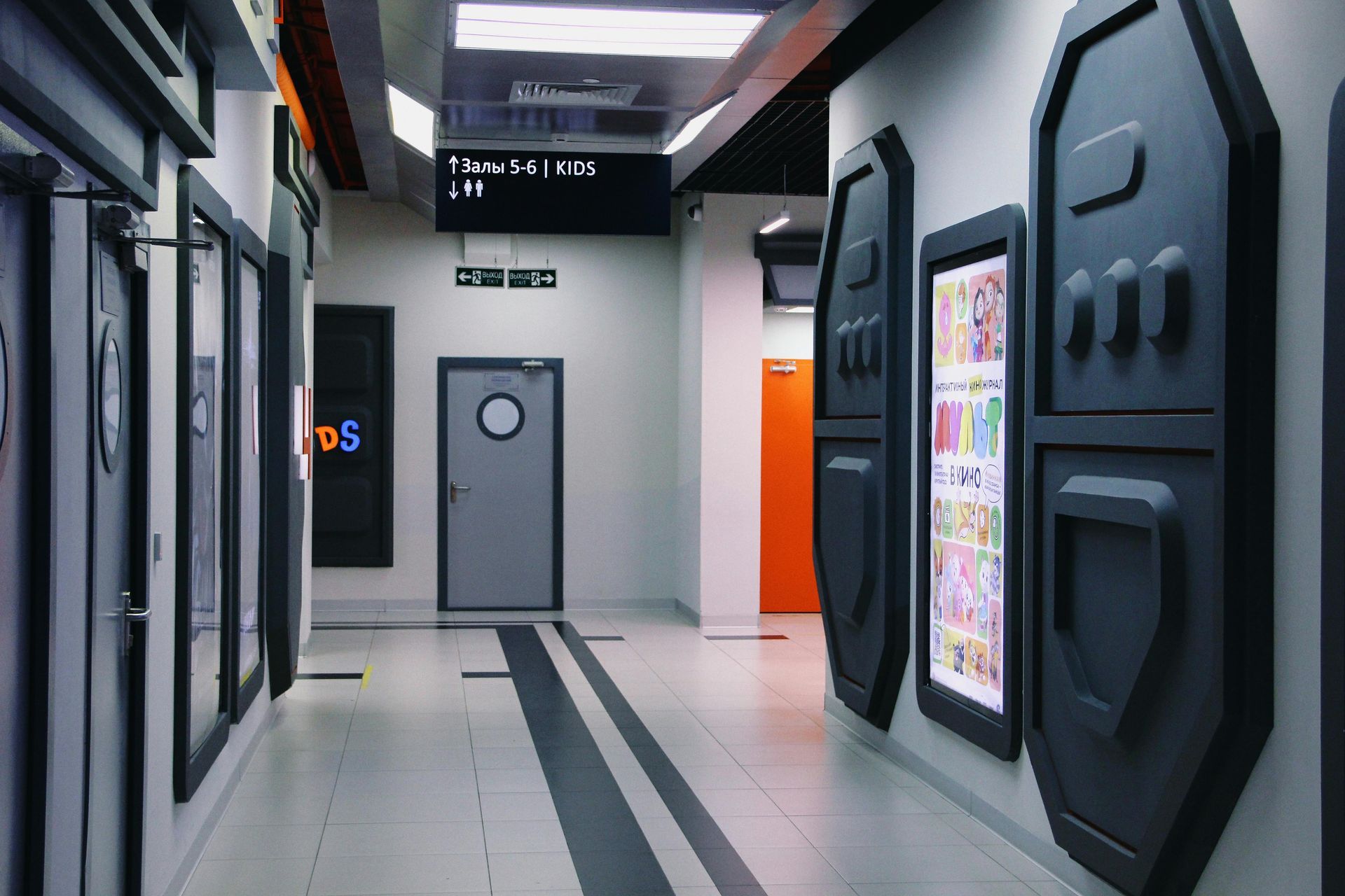 A long hallway with a lot of doors and signs on the wall.