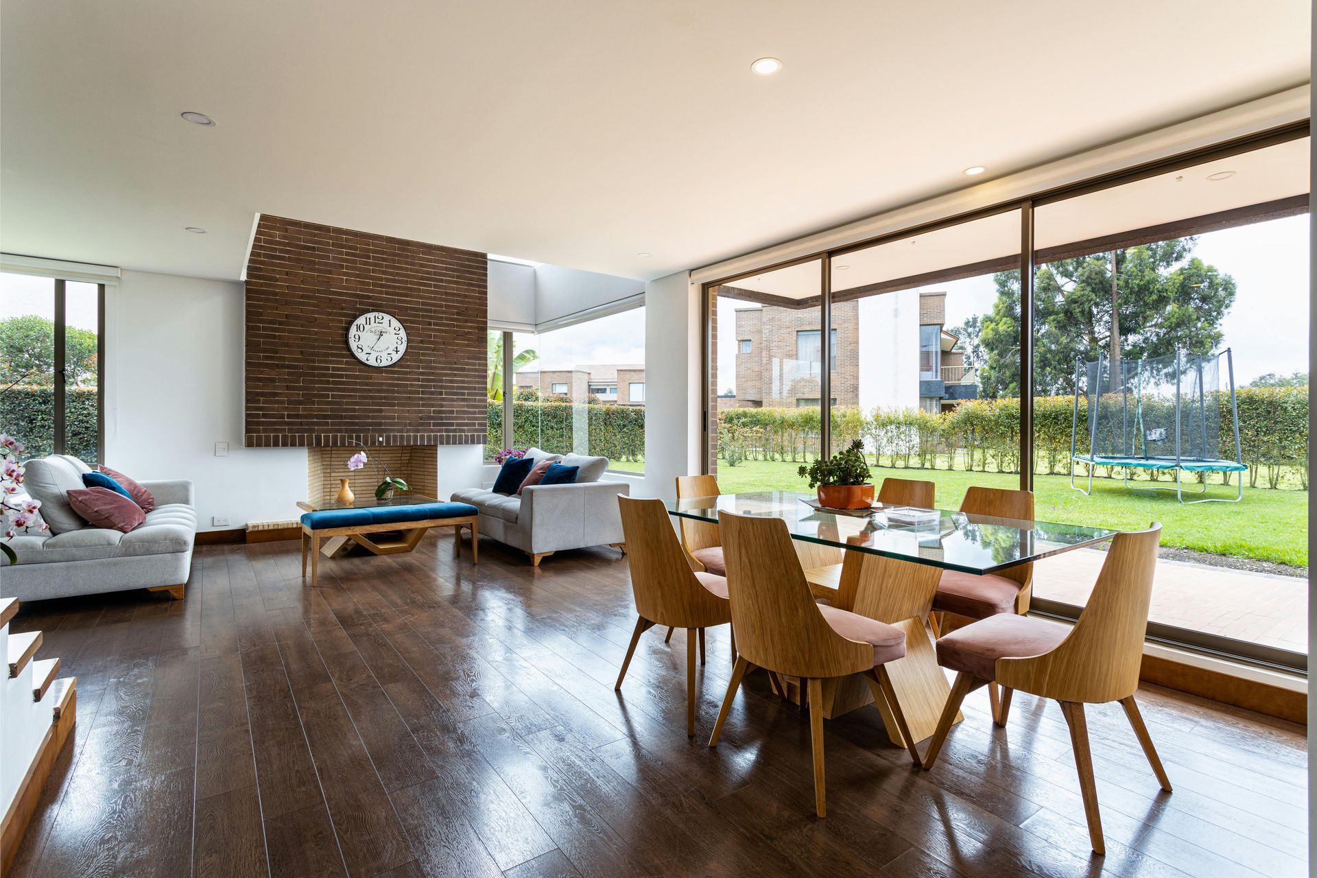 A living room with a dining table and chairs and a clock on the wall.
