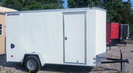 White enclosed cargo trailer with a single door and black tongue on a sunny day.